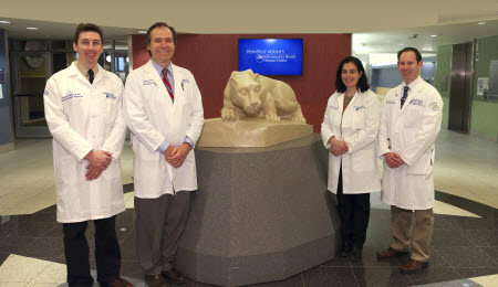 Four physicians from Penn State Hershey Inflammatory Bowel Disease Center team at Nittany Lion statue: Left to right: Andrew Tinsley, MD, Walter A. Koltun, MD, FACS, FASCRS, chief, Division of Colon and Rectal Surgery, professor of surgery; Emmanuelle Williams, MD, assistant professor of medicine; and Marc Schaefer, MD, PhD, associate professor of medicine