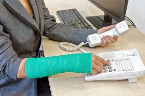 Photo of woman with a cast on her forearm and wrist dailing a telephone.