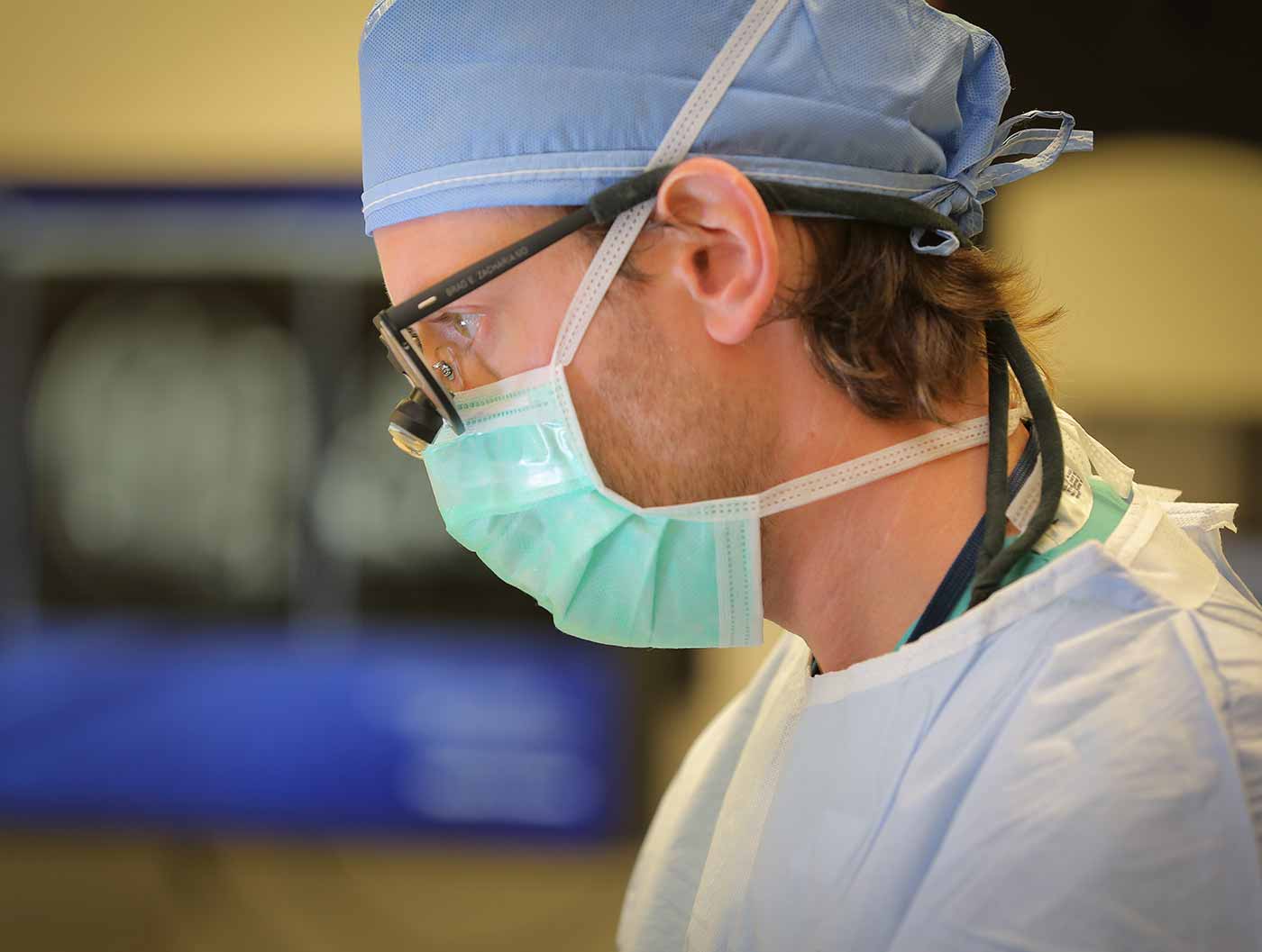 A close-cropped profile photo of Dr. Zacharia. He is wearing surgical attire.