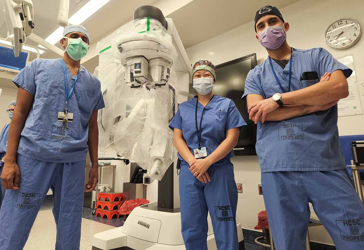 Penn State Health otolaryngologist ─ head and neck surgeons, from left, Dr. Neerav Goyal, Dr. Karen Choi and Dr. Guy Slonimsky are standing with the da Vinci SP robotic surgical system positioned in the background.